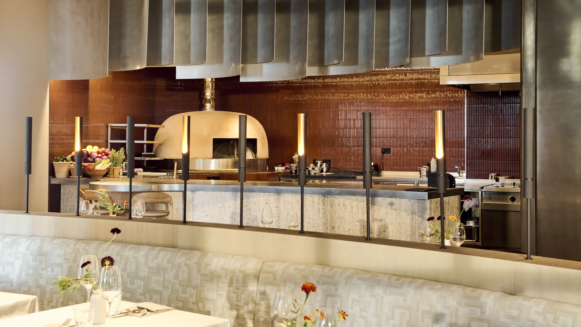 The open tabun oven and charcoal grill in the open kitchen at Kāio, seen across the dining room